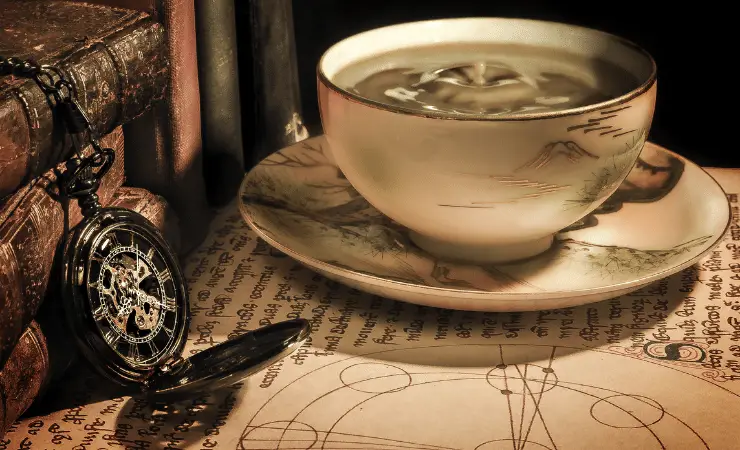 A cup of coffee next to a black compass on top of a paper map with a drawn compass.