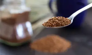 Up close view of instant coffee granules on a silver spoon.