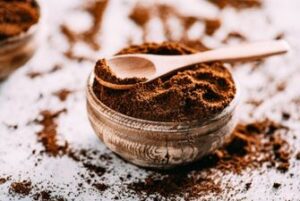 A beautiful silver bowl filled with coffee grounds with a large spoon on top.