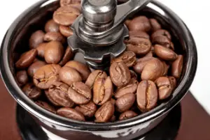 Close up view of whole coffee beans inside a grinder.