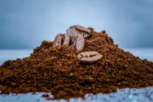 A pile of ground coffee with whole bean coffee beans on top of the pile.