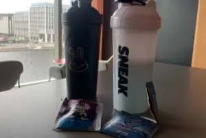 Two Sneak Shakers with two opened Sachets on a countertop to taste test for our Sneak Energy Review.